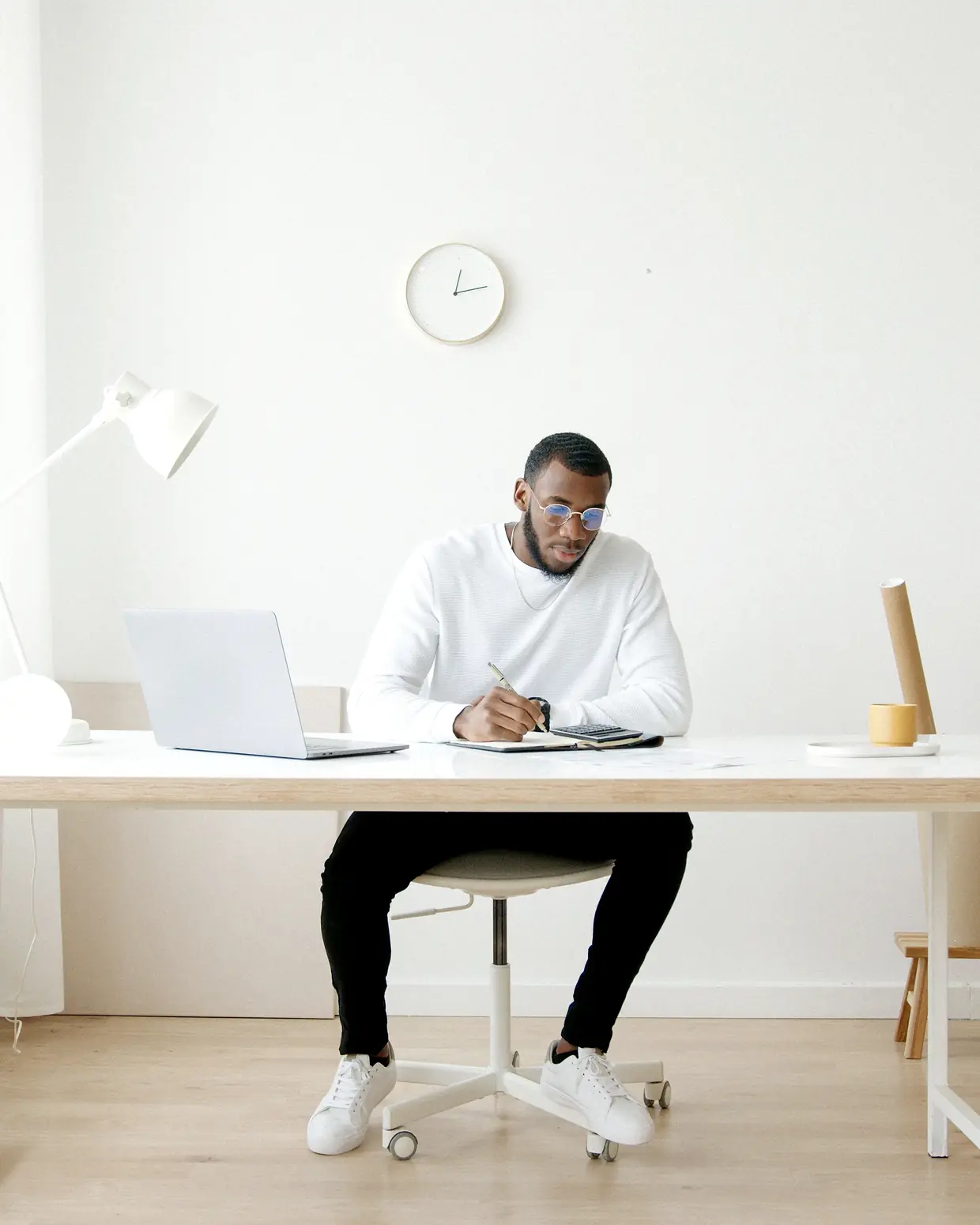 A desk with a closed laptop, a mug and upright document files.